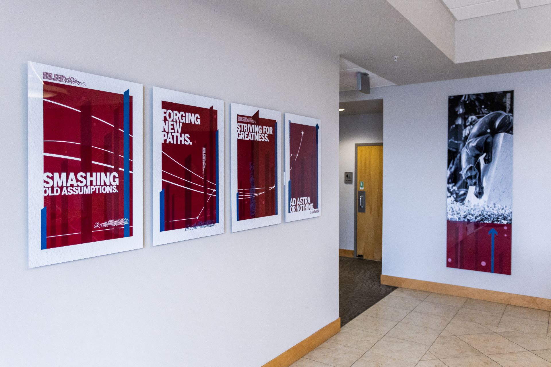Hallway with motivational posters at Florida Tech, featuring phrases like 'Smashing Old Assumptions' and 'Striving for Greatness